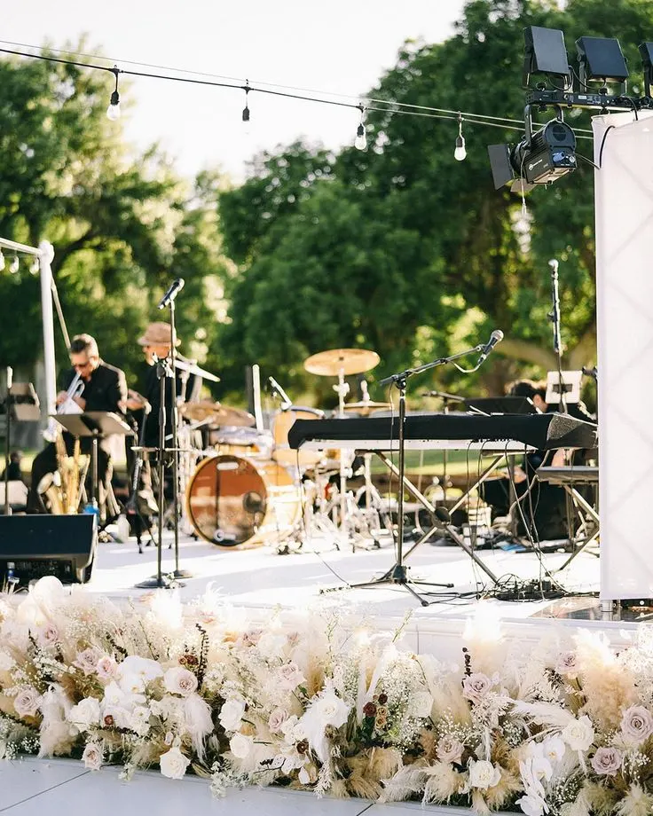 Outdoor stage with musicians & florals.